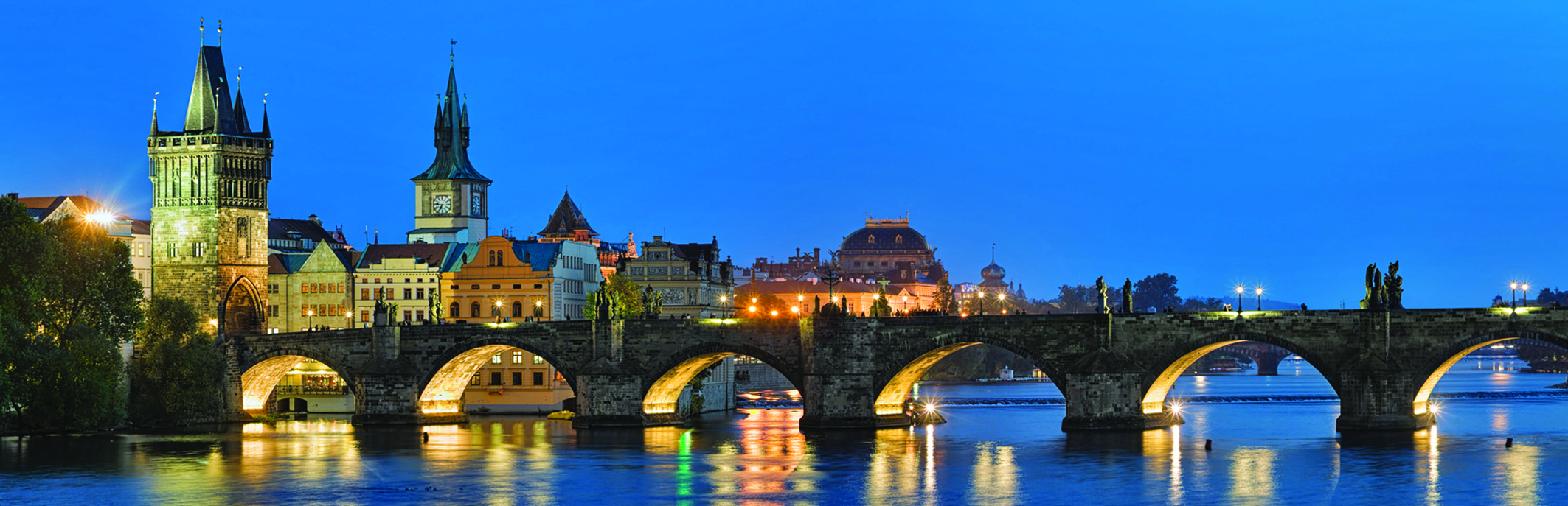 Evening panorama of the Charles Bridge in Prague, Czech Republic, with Old Town Bridge Tower, Old Town Water Tower and dome of the National Theatre